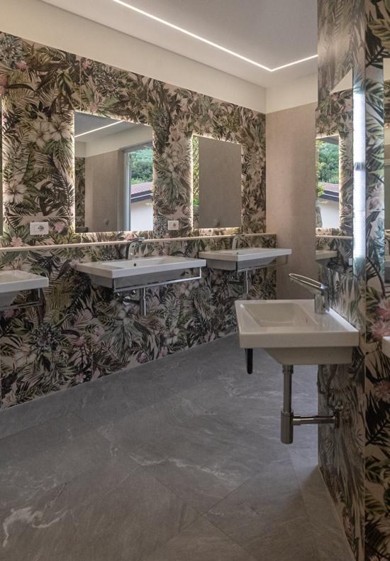 Moderne badkamer met tropisch behang en verlichte spiegels.
